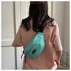Macaron green nylon crossbody bag with fashion patch shown on female model's back