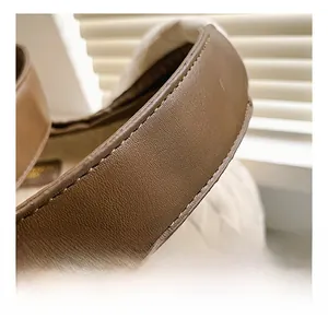 Detailed close-up of brown leather shoulder strap with neat stitching on white quilted bag