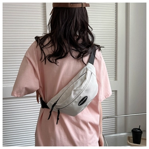 Close-up of white canvas crossbody bag with adjustable strap and fashion logo