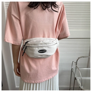 Detail of white nylon waist bag with black fashion logo on pink and white outfit