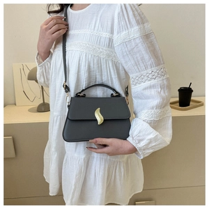Détails d'un sac à main gris foncé avec un fermoir doré élégant en forme de feuille