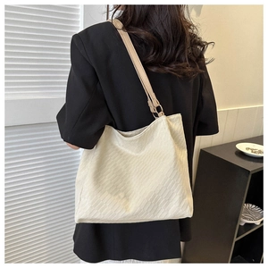 Detail of cream corduroy tote bag featuring striped texture and gold ring hardware