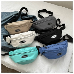 Flat lay of canvas crossbody waist bags in six various colors with adjustable black straps