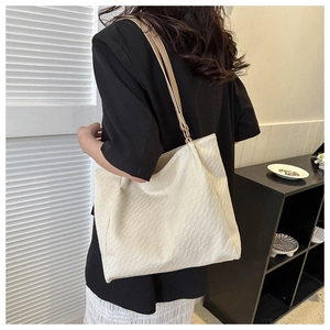 Detail view of cream woven tote bag showing checkerboard texture and golden metal buckle