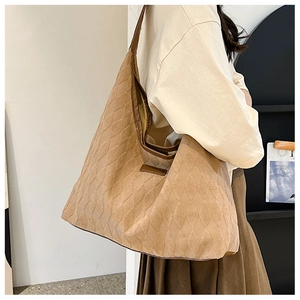 Detailed macro shot of large beige quilted suede tote bag with brown leather shoulder strap