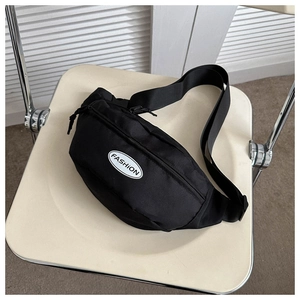 Close-up of black nylon crossbody bag featuring a white Fashion logo on a white chair
