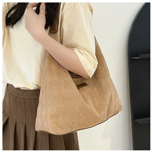 Detail shot of the quilted diamond texture and brown straps on a casual tote bag