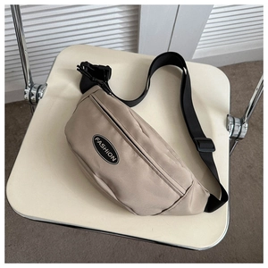 Detail of minimalist beige nylon crossbody bag with fashion label on white chair