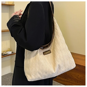 Detail of quilted canvas tote bag with brown leather handles and brand logo tag