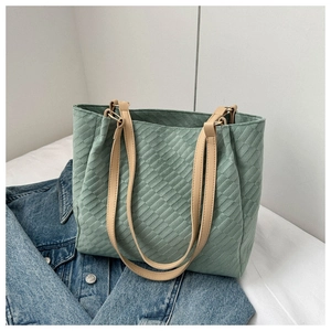 Detail of light green quilted tote bag with beige handles and golden metal ring hardware