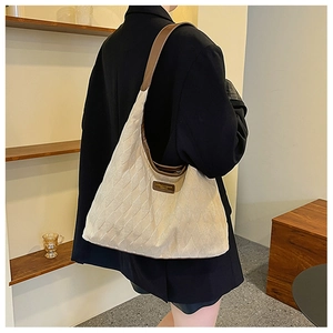 Detail of quilted corduroy tote bag showing contrast leather trim and logo patch