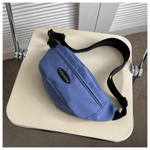Close-up of haze blue canvas fanny pack with black adjustable strap on a chair