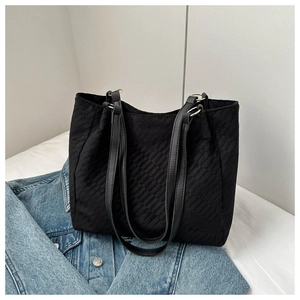 Detail of black quilted tote bag with golden metal rings on blue denim jacket