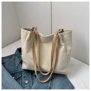 Detail of cream white tote bag featuring unique brick-like texture and brown shoulder straps