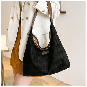 Close-up of a black quilted hobo bag with a brown leather shoulder strap and logo plaque