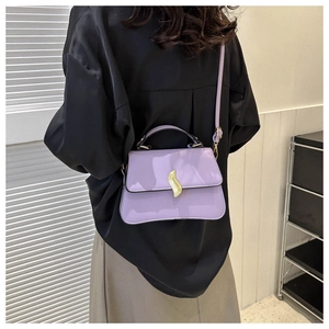 Détail du sac à main violet en similicuir avec fond incurvé et fermoir flamme dorée