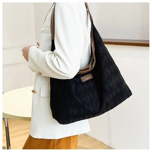 Close-up of quilted black tote bag with brown leather strap and fashion leather tag