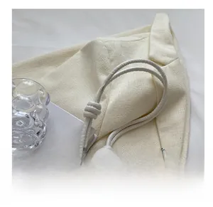 Close-up of pleated shoulder bag with knotted strap and silver-tone metal charm detail
