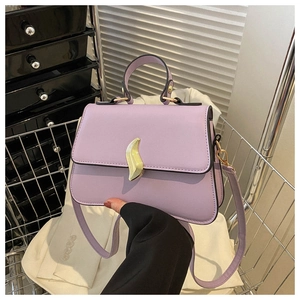 Détail d'un sac à main violet clair avec une boucle métallique dorée en forme de vague