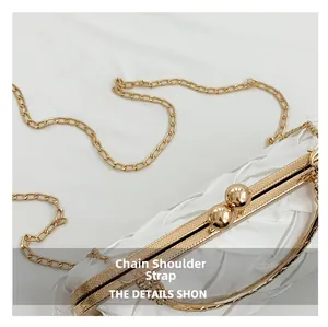 Close-up of white satin evening bag with pleated texture and golden chain strap