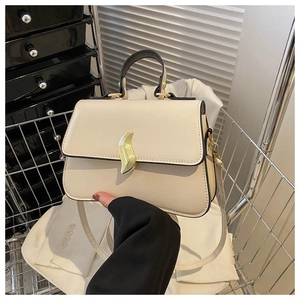 Gros plan sur un sac à main beige avec un fermoir métallique doré en forme de S élégant