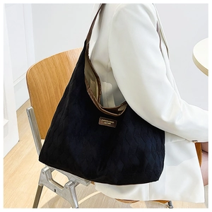 Detail of black quilted tote bag with brown leather trim and fashion brand tag