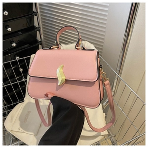 Détail du sac bandoulière rose clair avec boucle en métal en S et texture de cuir mat