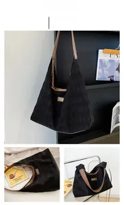 Close-up of black quilted tote bag with brown leather straps and metal logo detail
