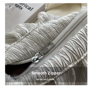 Macro detail of smooth silver metal zipper on premium white pleated shoulder bag