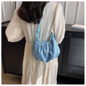 Light blue pleated cloud bag with silver floral chain shown on shoulder from behind