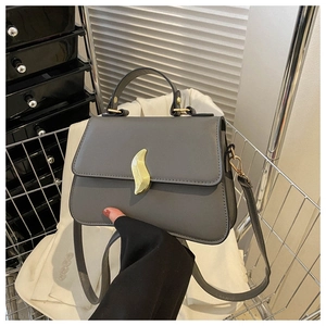 Détail d'un sac à main gris foncé en cuir avec boucle dorée dans un panier en métal