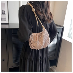 Pink pleated underarm bag featuring a knotted strap and decorative metallic flower chain