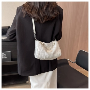 Détail d'un sac à main blanc plissé avec chaîne élégante en perles et métal argenté