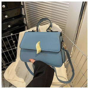 Détail du sac bandoulière bleu clair avec boucle vague dorée et structure en accordéon