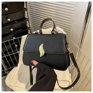 Détail d'un sac bandoulière noir avec boucle feuille dorée et bandoulière réglable