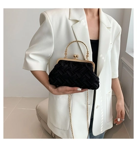 Detail of black woven crossbody bag with golden ring handle and chain strap for women