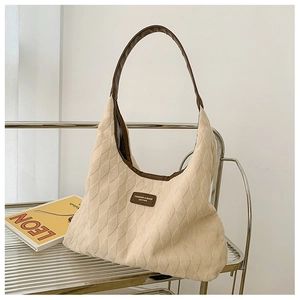 Detailed shot of beige quilted canvas tote bag with brown leather handles and brand tag