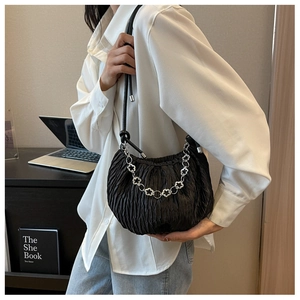 Close-up of pleated black cloud bag featuring a silver floral chain strap detail
