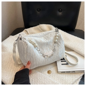 Détail du sac à main blanc plissé avec une élégante chaîne de perles et fleurs