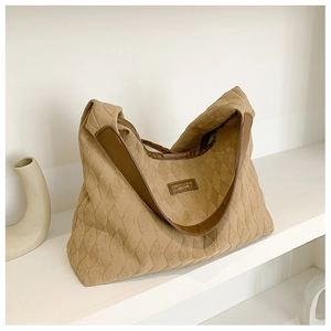 Detail of khaki quilted hobo bag featuring brown leather trim and fashion label texture