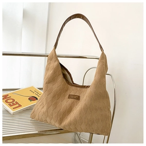 Detail of quilted diamond pattern on beige suede tote bag with brown leather strap