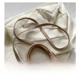 Detail der beigen geflochtenen Muscheltasche mit Doppelreißverschluss und Lederriemen