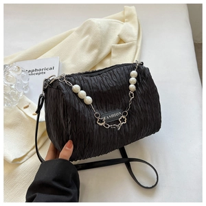Détail du sac à bandoulière plissé noir avec chaîne en perles et breloque logo mode