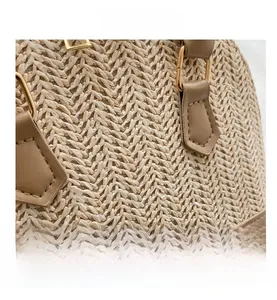 Detailansicht der Stroh-Handtasche mit Ledergriff und goldenen Metallringen