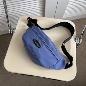 Blue sporty nylon crossbody chest bag with adjustable strap and FASHION label on chair