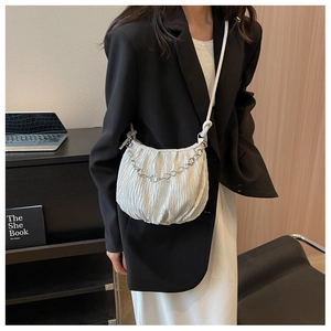 Detail of white pleated shoulder bag featuring silver chain and adjustable knotted strap