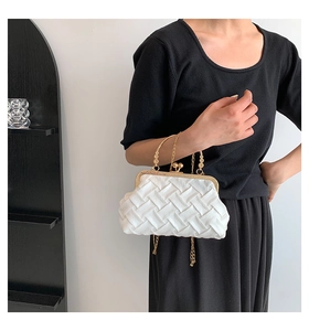 Detailed close-up of white woven texture with gold vintage metal clasp and chain strap