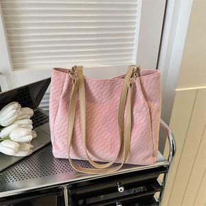 Pink woven tote bag with brown leather straps displayed in a chic lifestyle setting