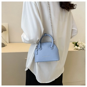 Detail of light blue litchi grain leather shell bag with beaded chain strap on a model