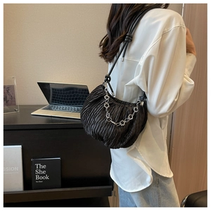 Detail of black pleated shoulder bag with silver floral chain and knotted strap detail